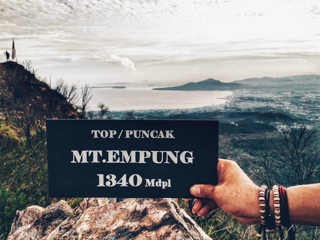 Papan tulisan ketinggian Gunung Empung, dengan latar belakang pemandangan Gunung Empung di Tomohon.